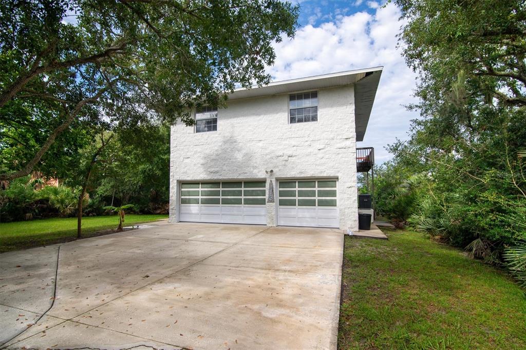 A two-story white stone building with two garage doors and a concrete driveway — 1835 OAK PLACE, FLAGLER BEACH, FL