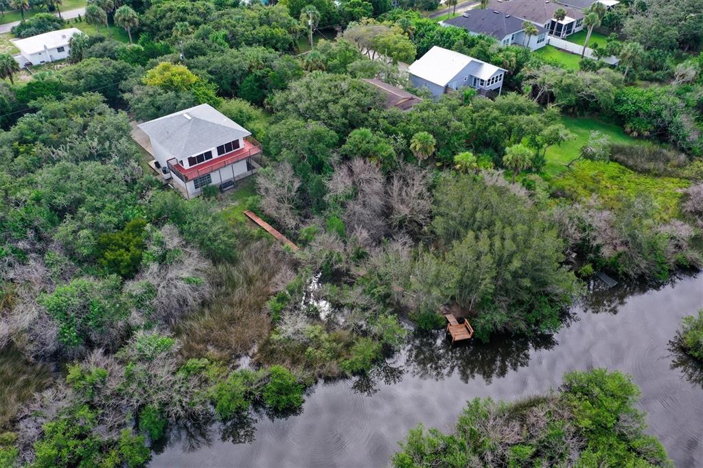 An aerial view shows a house with a deck and a wooden walkway leading to a dock — 1835 OAK PLACE, FLAGLER BEACH, FL