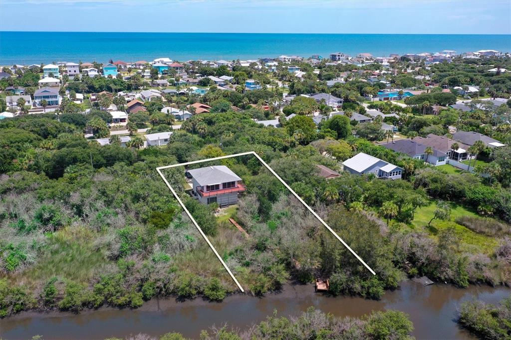 An aerial view shows a house situated on a wooded lot bordering a small waterway — 1835 OAK PLACE, FLAGLER BEACH, FL