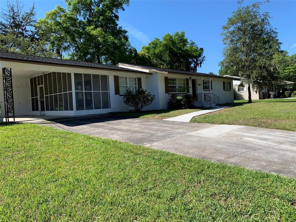 A white single-story house with brown shutters, a red front door, and a concrete walkway — 1106 NE 17TH TERRACE, OCALA, FL