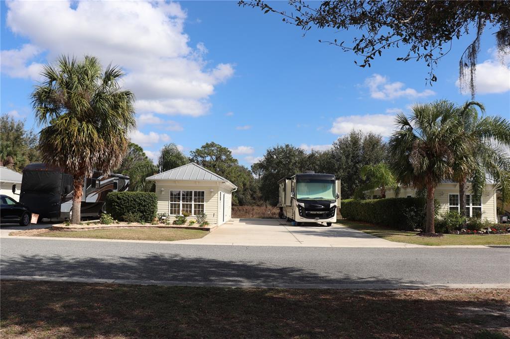 Two recreational vehicles are parked on concrete pads next to small, light-colored accessory buildings — 9573 SE 49TH TERRACE, WEBSTER, FL