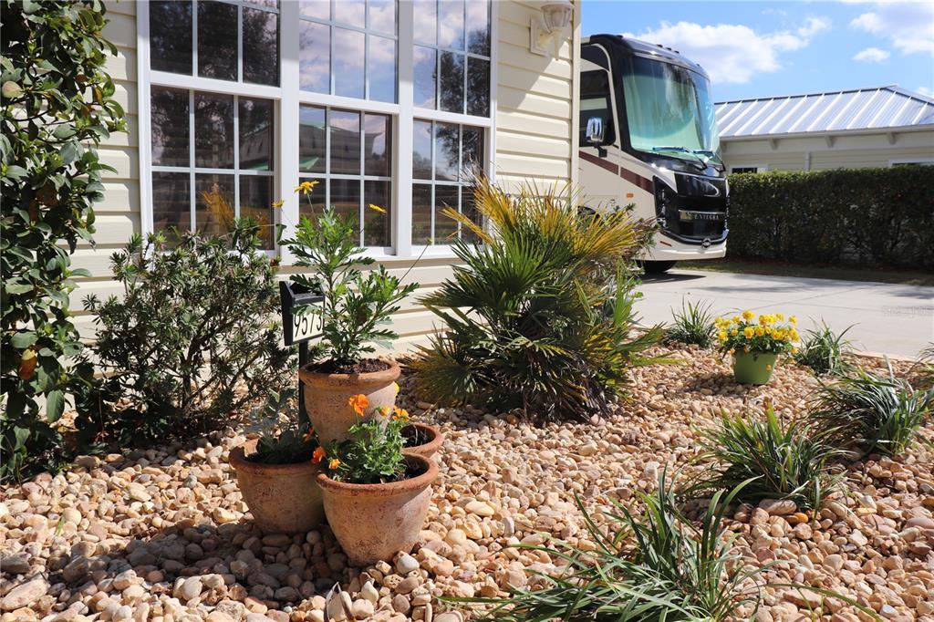 A house exterior features a rock garden with potted plants and a parked motorhome nearby — 9573 SE 49TH TERRACE, WEBSTER, FL