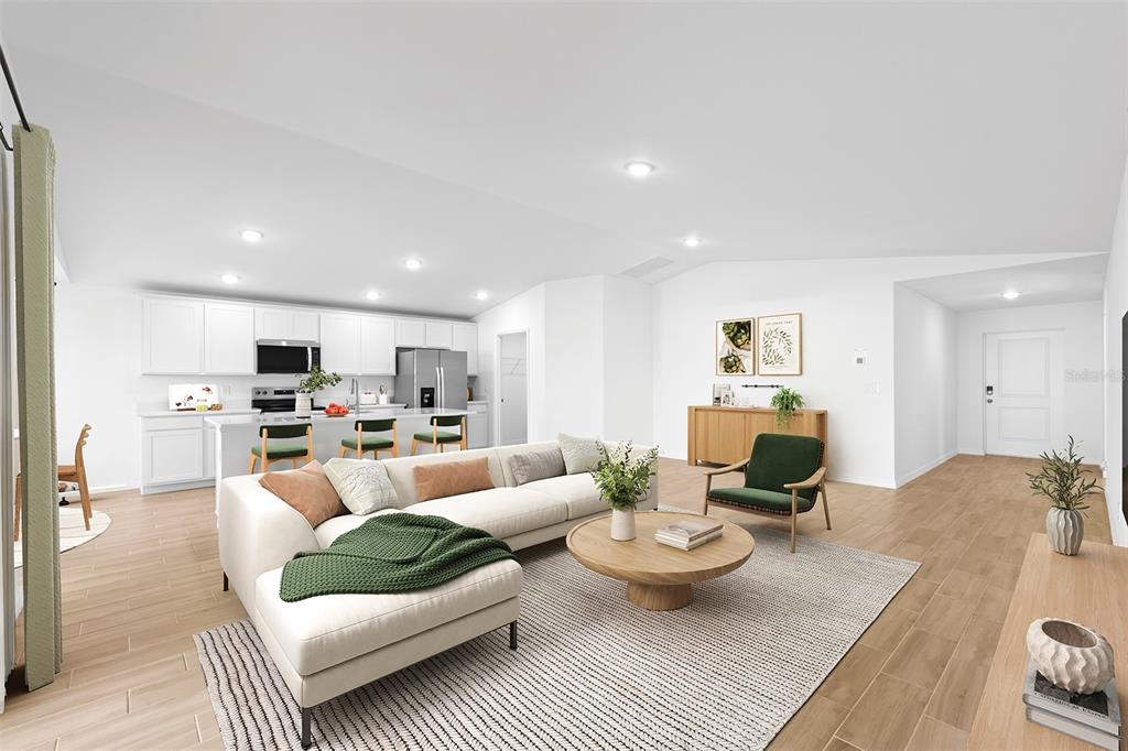 A bright, open-concept living room and kitchen featuring white cabinetry, light wood flooring, and furniture — 2860 W BUCCANEER LANE, CITRUS SPRINGS, FL