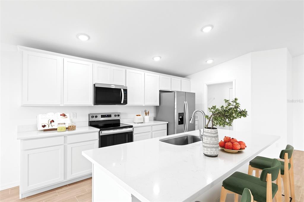 A modern kitchen features white cabinets, stainless steel appliances, and a large white quartz island — 2860 W BUCCANEER LANE, CITRUS SPRINGS, FL