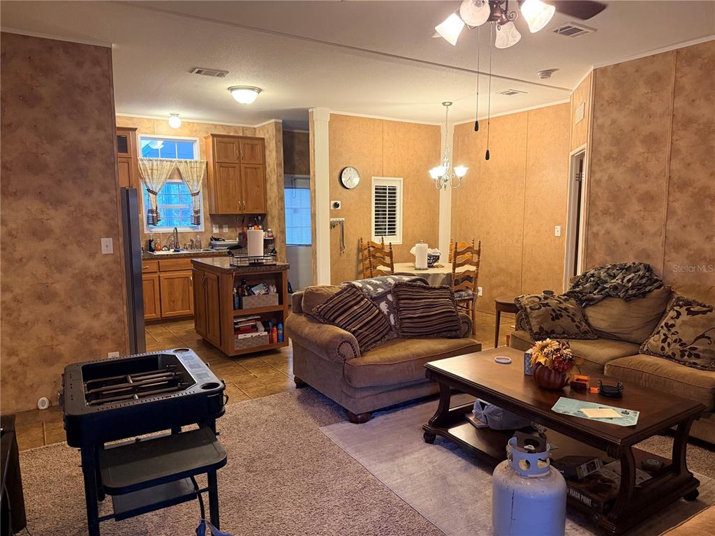 An open-concept living room and kitchen featuring wood-paneled walls, tile flooring, and brown furniture — 21809 SUNSET DRIVE, ASTOR, FL