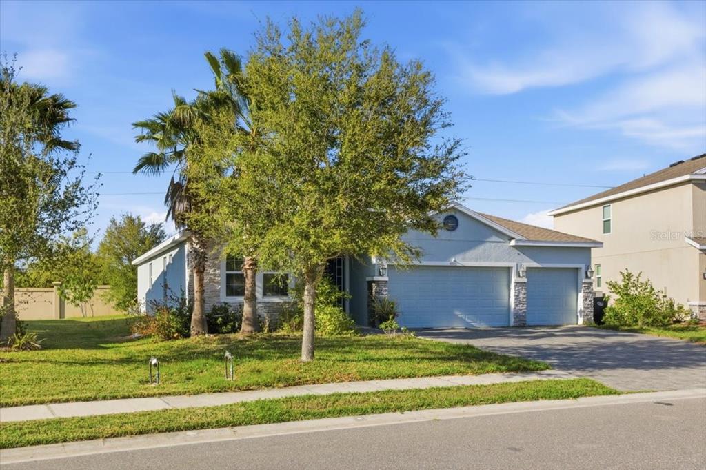 A single-story house with a light blue exterior, a three-car garage, and a front yard — 6702 DEVESTA LOOP, PALMETTO, FL