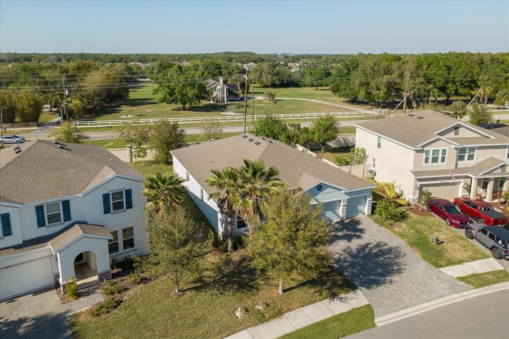 An aerial view shows three suburban houses with driveways and a large grassy field beyond — 6702 DEVESTA LOOP, PALMETTO, FL