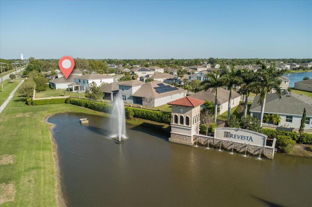 An aerial view shows a pond with a fountain and the Trevesta community entrance sign — 6702 DEVESTA LOOP, PALMETTO, FL