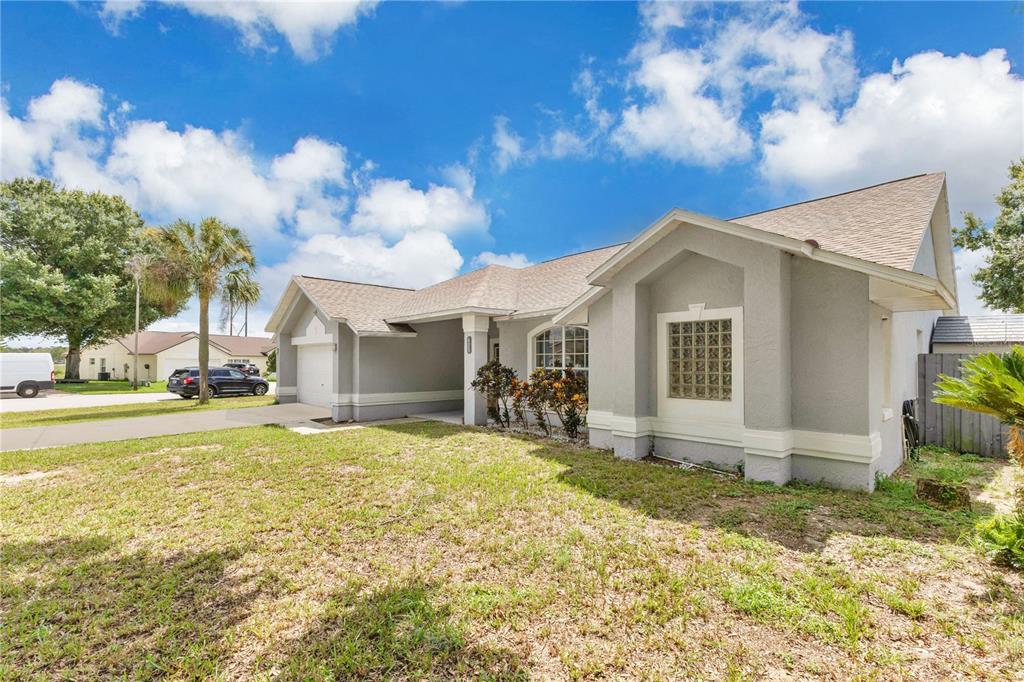 A single-story gray house with a glass block window and a two-car garage — 623 OAKPARK LOOP, DAVENPORT, FL