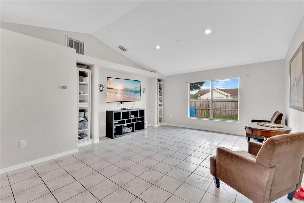 A living room features light tile flooring, a vaulted ceiling, and a wall-mounted television — 623 OAKPARK LOOP, DAVENPORT, FL