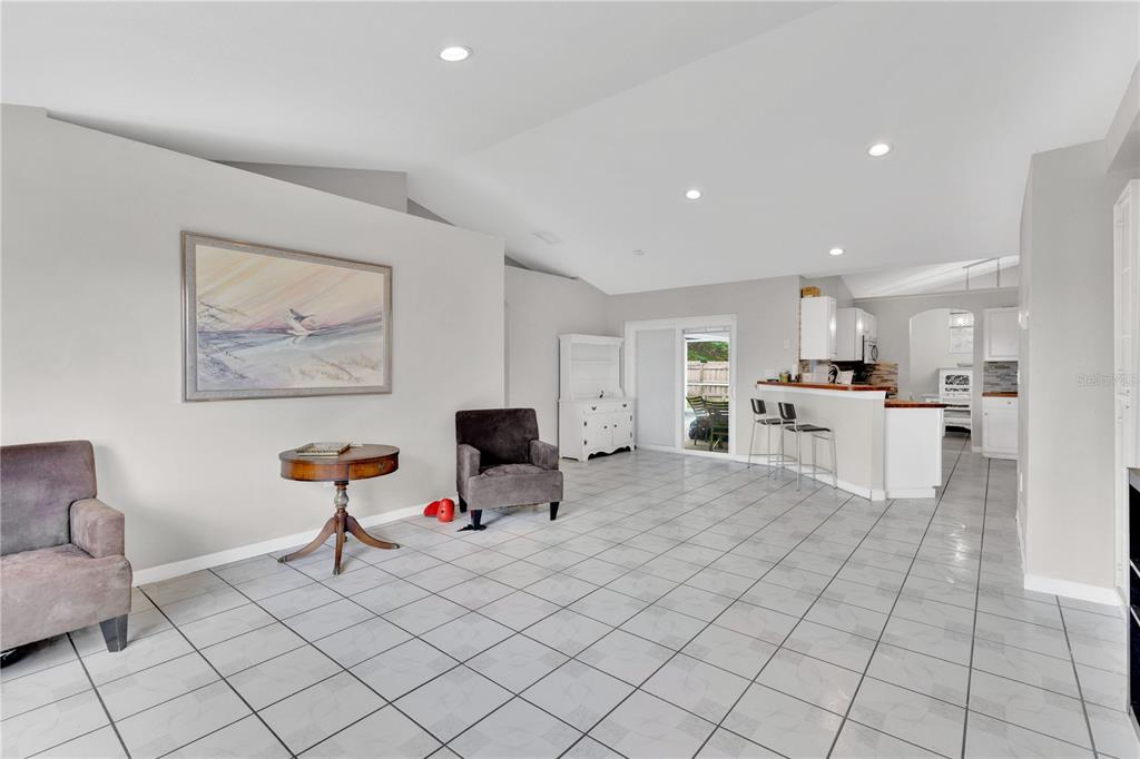A spacious living area with tile flooring, a vaulted ceiling, and an open kitchen — 623 OAKPARK LOOP, DAVENPORT, FL