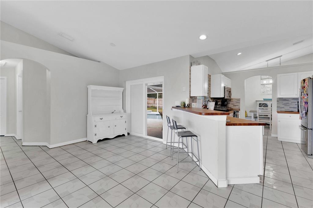 A kitchen and dining area with white cabinets, tile flooring, and a breakfast bar — 623 OAKPARK LOOP, DAVENPORT, FL