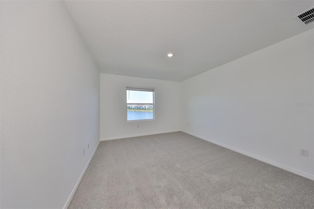An empty bedroom features white walls, gray carpeting, a single window, and a ceiling light — 379 MANGROVE SHADE CIRCLE, APOLLO BEACH, FL