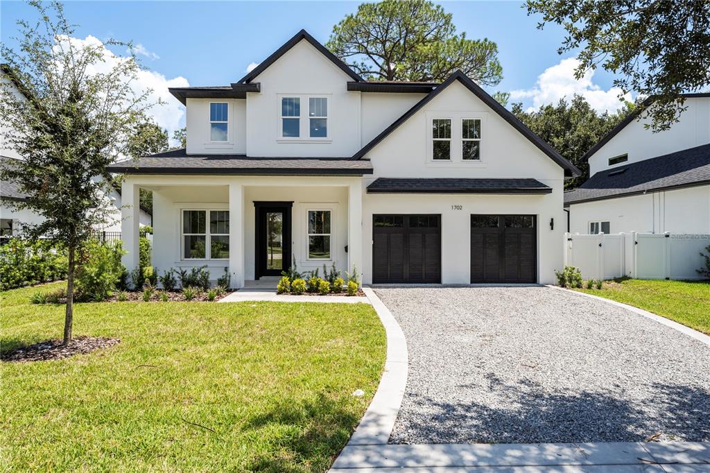 A white two-story house with a gravel driveway and black garage doors — 1702 ARBOR PARK DRIVE, WINTER PARK, FL