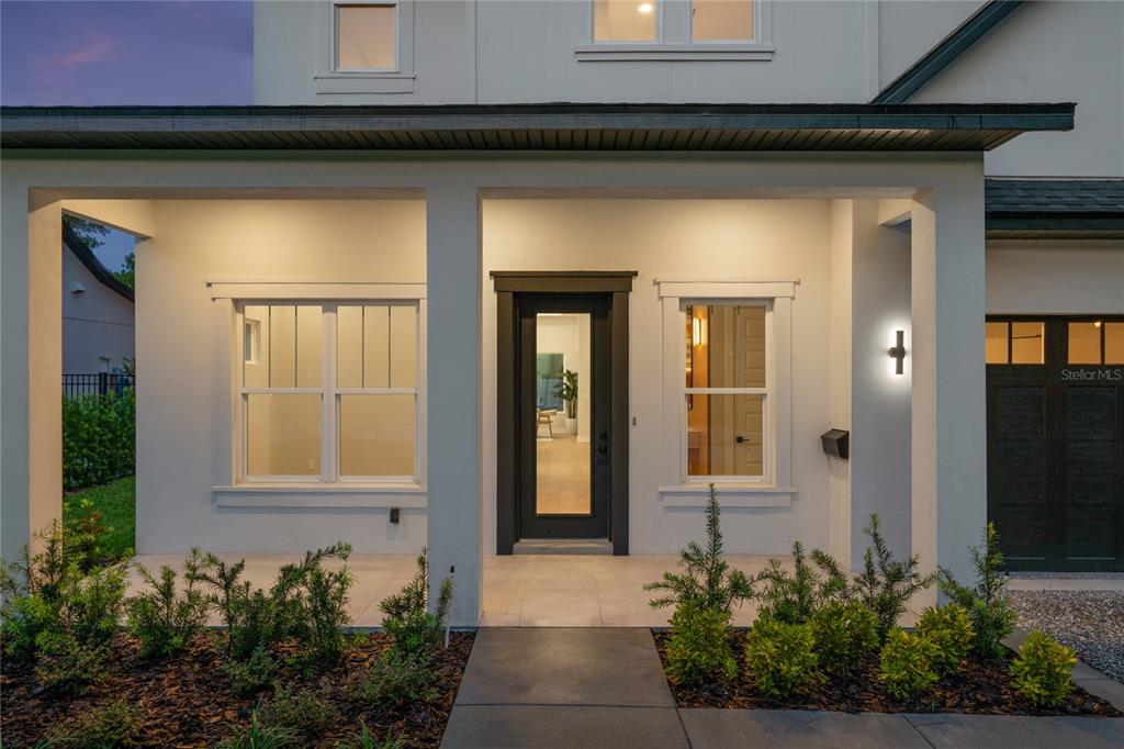 A modern home exterior features a covered porch, a dark front door, and white siding — 1702 ARBOR PARK DRIVE, WINTER PARK, FL