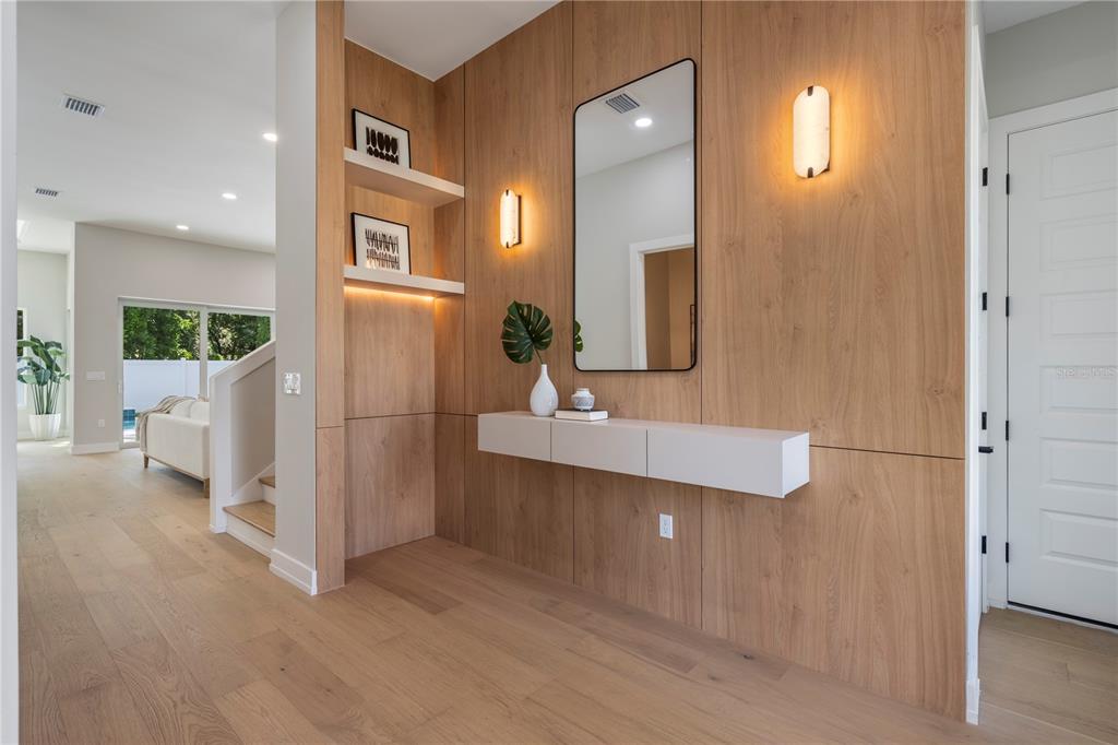 An entryway features wood-paneled walls, a floating console table, a mirror, and built-in shelving — 1702 ARBOR PARK DRIVE, WINTER PARK, FL