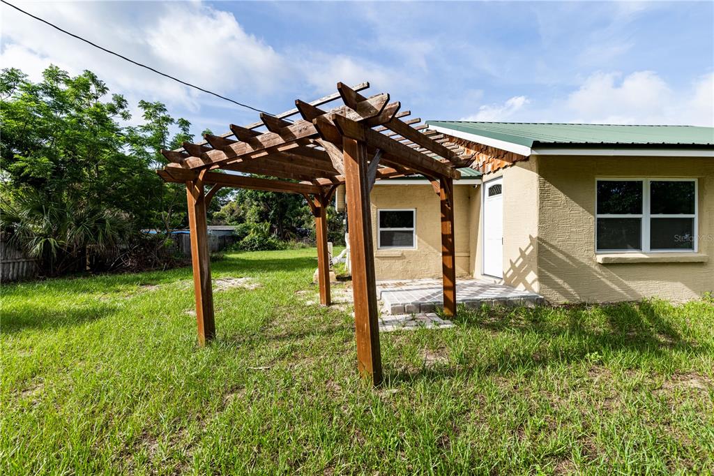 A small, tan-colored house with a green metal roof sits in a grassy yard — 7020 SCOTT AVENUE, MOUNT DORA, FL