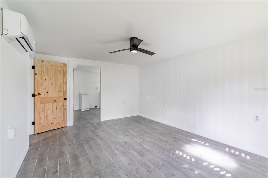 A room with white vertical paneling, gray tile flooring, a ceiling fan, and a wooden door — 7020 SCOTT AVENUE, MOUNT DORA, FL