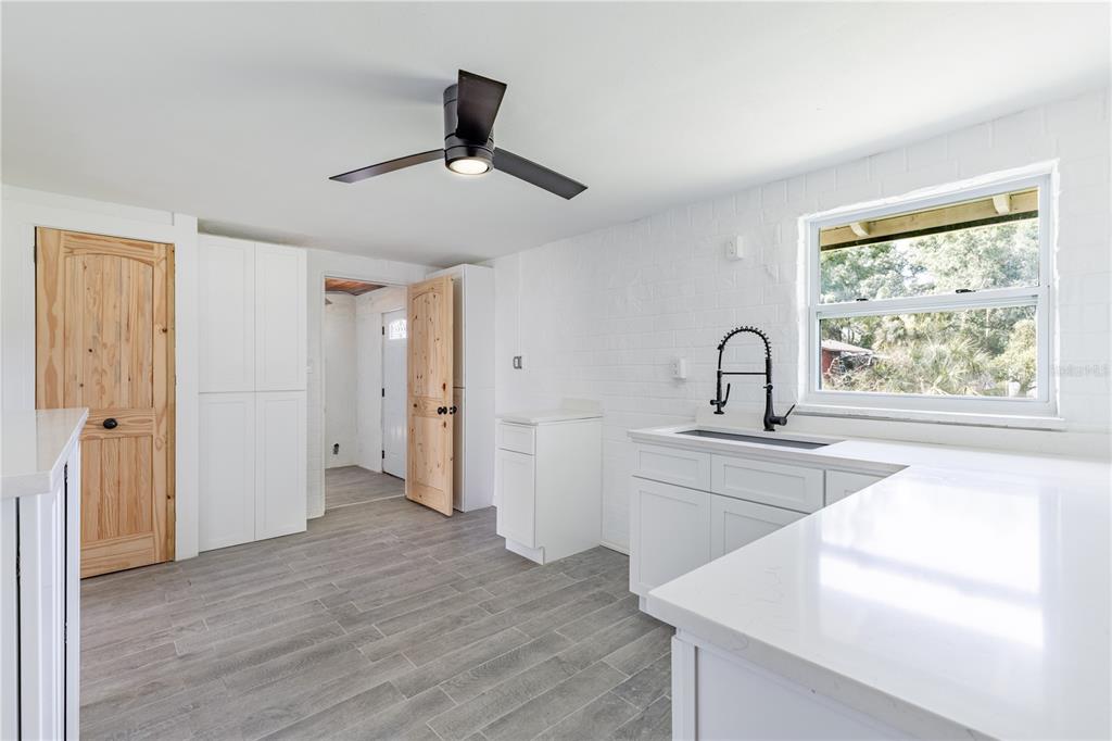 A kitchen with white cabinets, quartz countertops, a black faucet, and light wood doors — 7020 SCOTT AVENUE, MOUNT DORA, FL