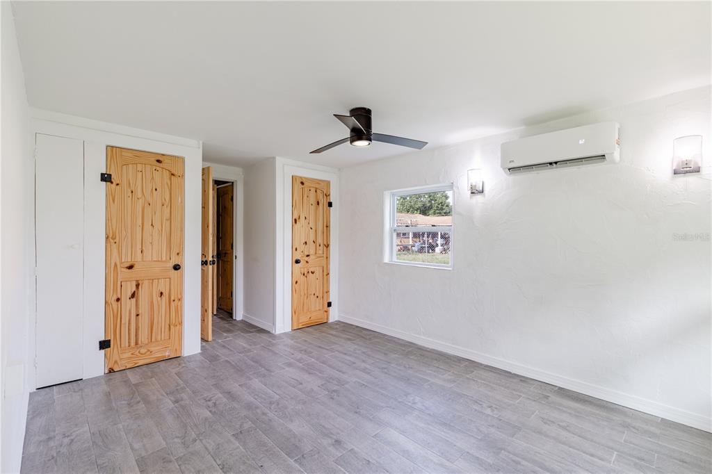 A room with gray tile flooring, white textured walls, wood doors, and a ceiling fan — 7020 SCOTT AVENUE, MOUNT DORA, FL