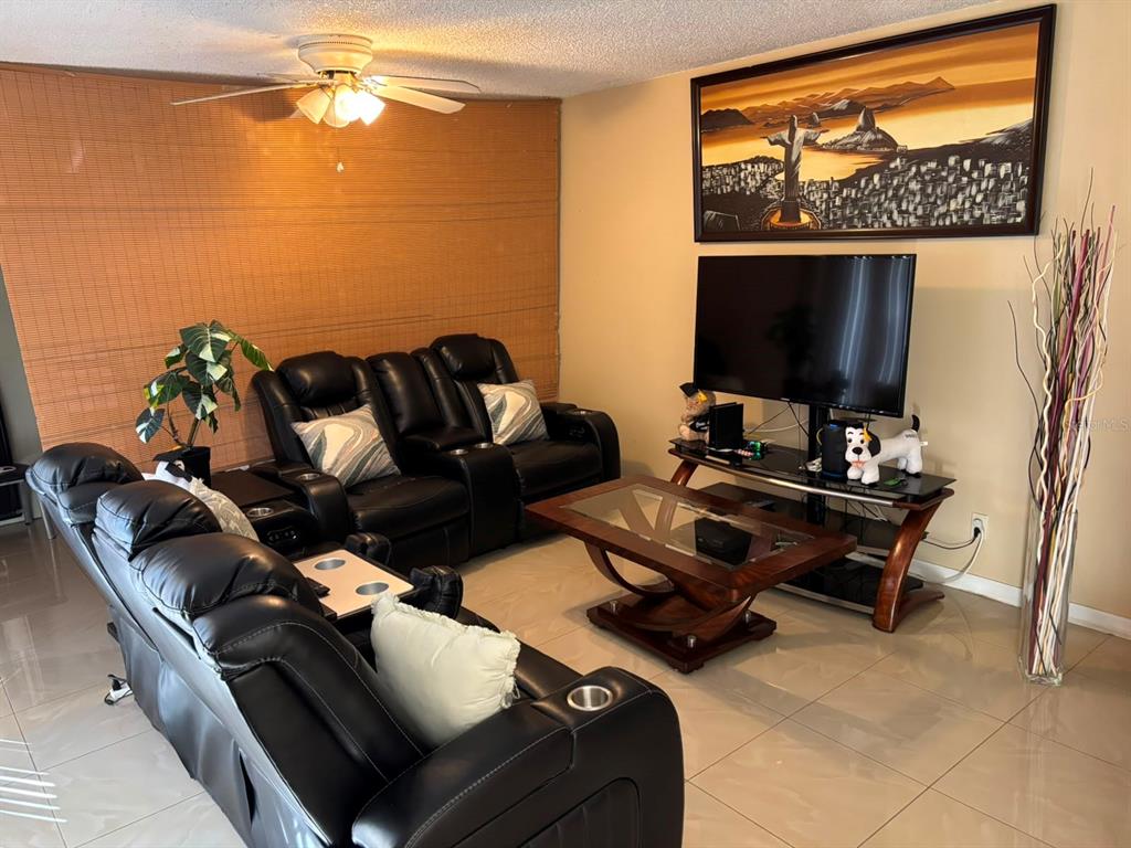 A living room features black leather reclining sofas, a glass coffee table, and a television — 5277 CORAL COURT UNIT 625, ORLANDO, FL
