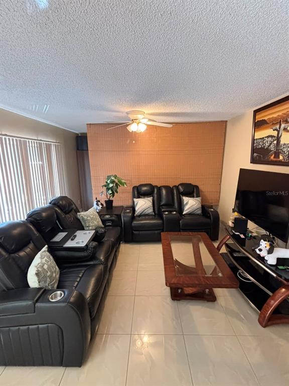 A living room features black leather reclining furniture, a glass-top coffee table, and tile flooring — 5277 CORAL COURT UNIT 625, ORLANDO, FL