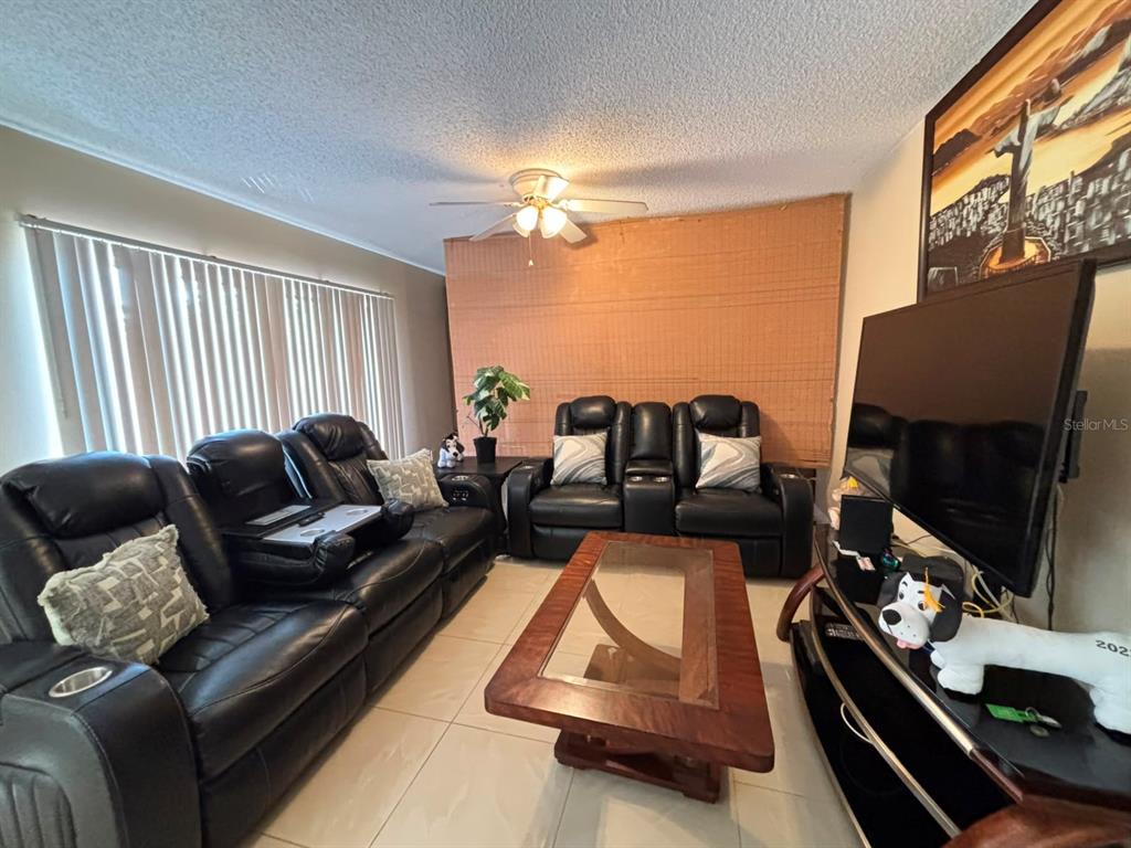 A living room features black leather reclining sofas, a wooden coffee table, and tile flooring — 5277 CORAL COURT UNIT 625, ORLANDO, FL
