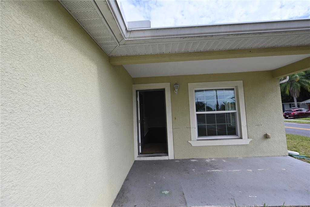 A covered concrete porch leads to an open front doorway next to a single window — 5302 SCHOOL ROAD, NEW PORT RICHEY, FL