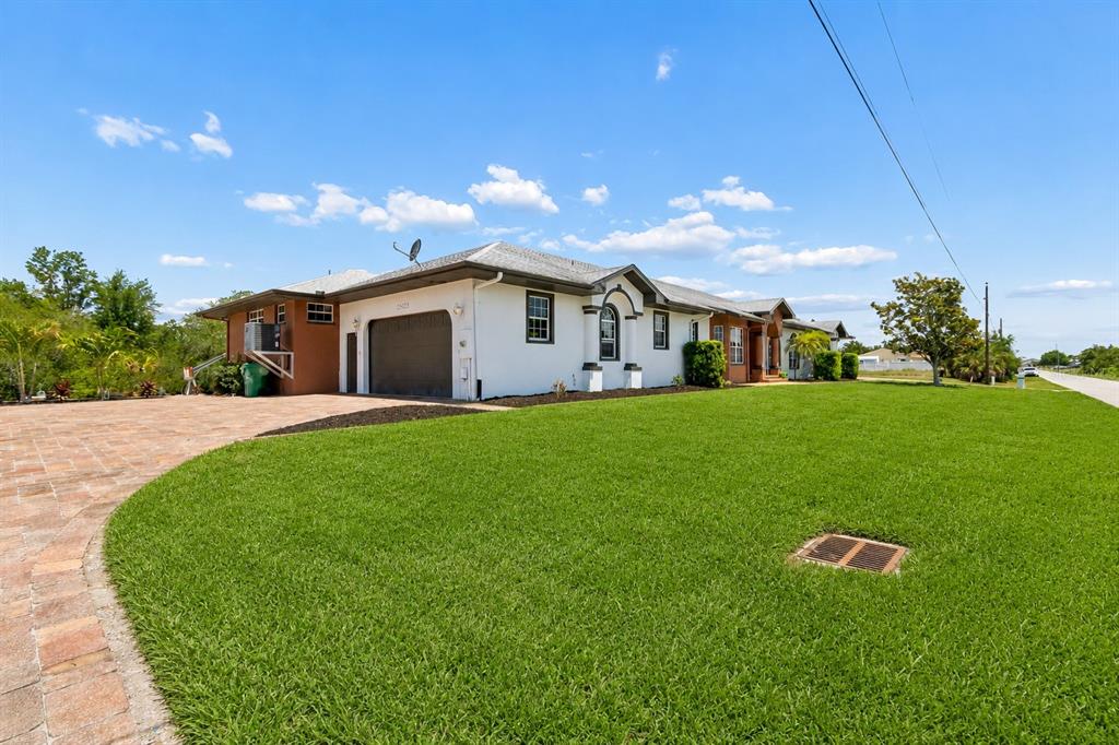 A single-story house with a white exterior, dark garage door, and a paved driveway — 3339 DESOTO DRIVE, PUNTA GORDA, FL