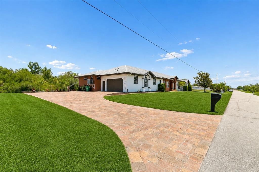 A single-story house with a paved driveway and a large green lawn under a blue sky — 3339 DESOTO DRIVE, PUNTA GORDA, FL