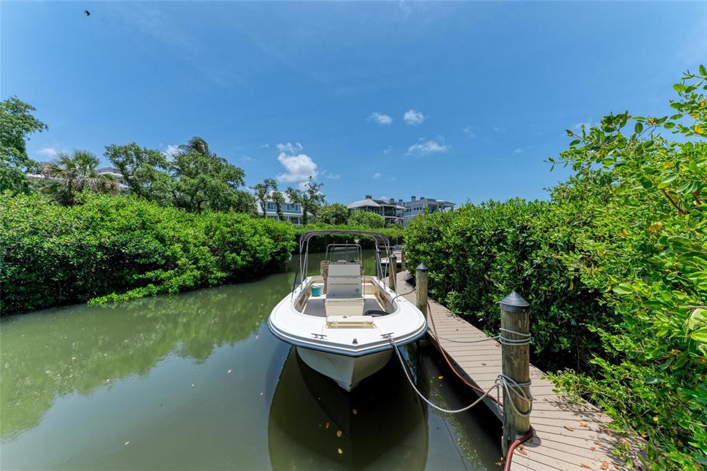 An aerial view shows a two-story house with a metal roof surrounded by lush trees — 8963 FISHERMENS BAY DRIVE, SARASOTA, FL