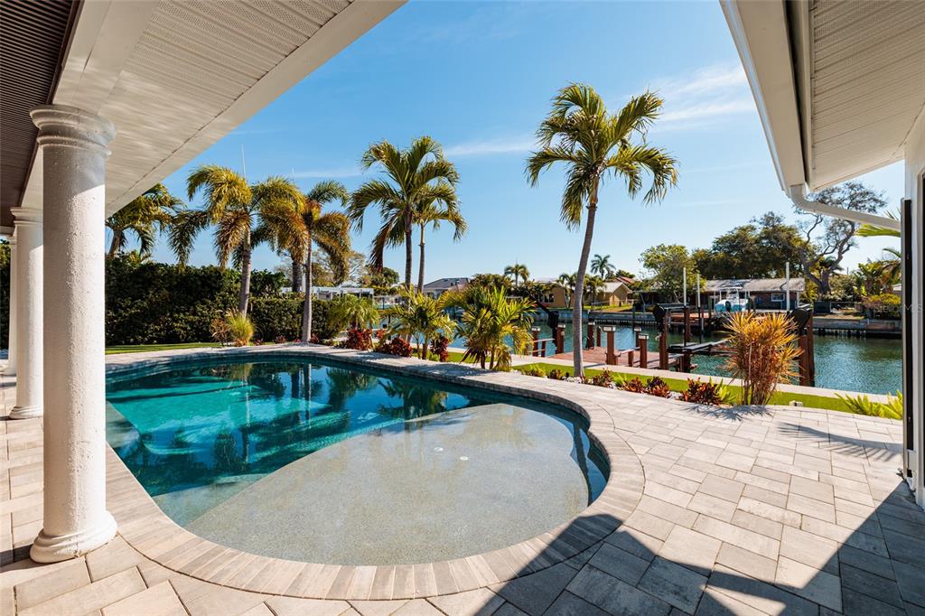 A swimming pool with a sun shelf overlooks a canal with a private boat dock — 2032 KANSAS AVENUE NE, ST PETERSBURG, FL