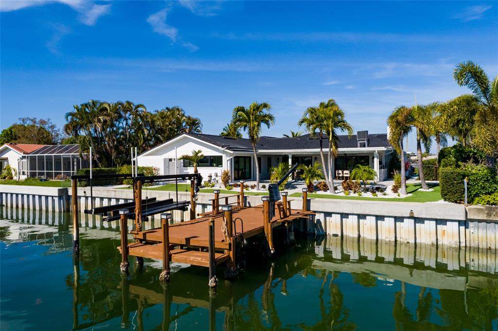 A white house with a boat dock sits along a canal under a blue sky — 2032 KANSAS AVENUE NE, ST PETERSBURG, FL