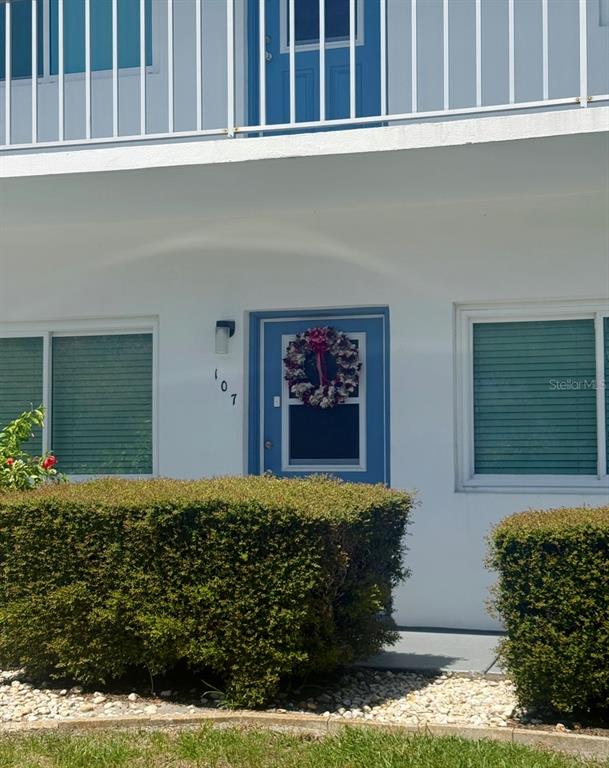 A white building exterior features a blue front door with a wreath and unit number — 8080 112TH STREET UNIT 107, SEMINOLE, FL