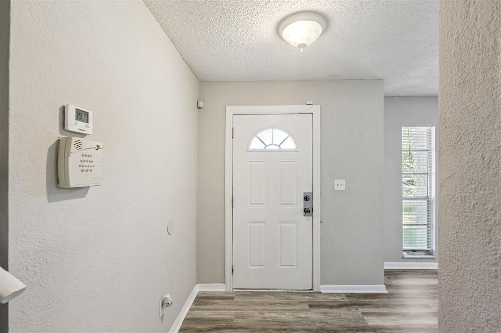 An entryway with white tile floors opens into a living area with beige tile flooring — 4035 WENDY DRIVE, ORLANDO, FL