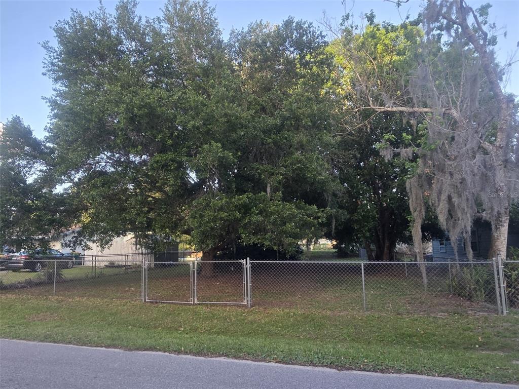 A fenced, tree-covered vacant lot sits along a paved road — 722 NEVADA STREET, MELBOURNE, FL