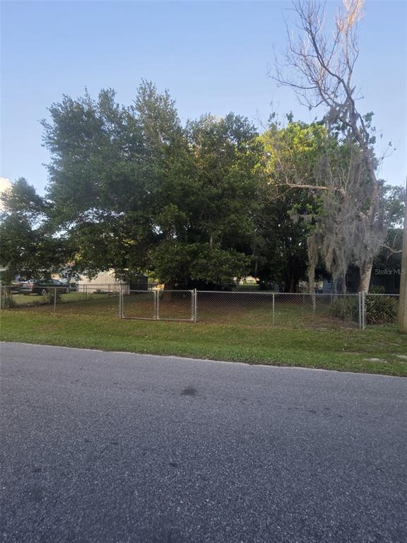 A chain-link fence encloses a grassy lot with several large, mature trees — 722 NEVADA STREET, MELBOURNE, FL
