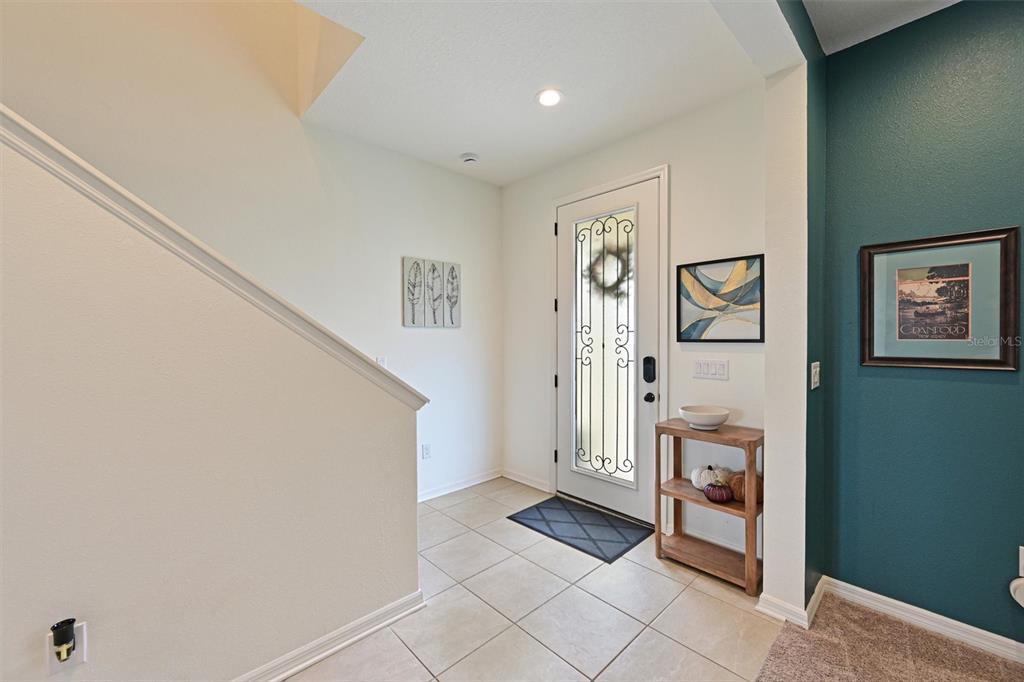A tiled entryway features a white front door, a wooden console table, and teal walls — 11124 MOONSAIL DRIVE, PARRISH, FL