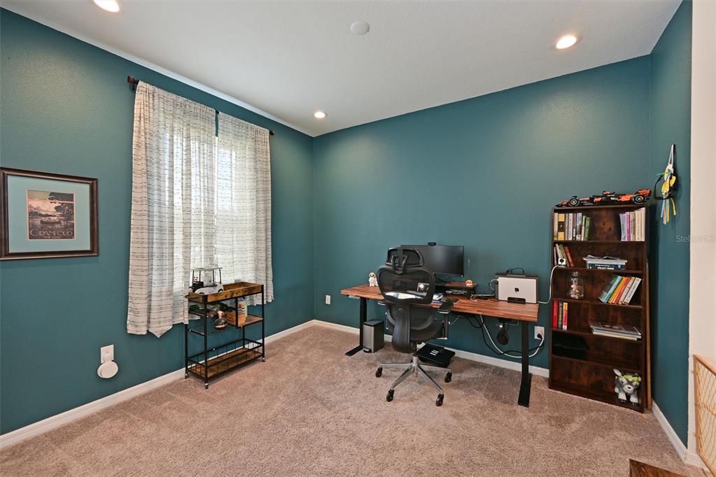 A home office features teal walls, a wooden desk, a bookshelf, and a window with curtains — 11124 MOONSAIL DRIVE, PARRISH, FL