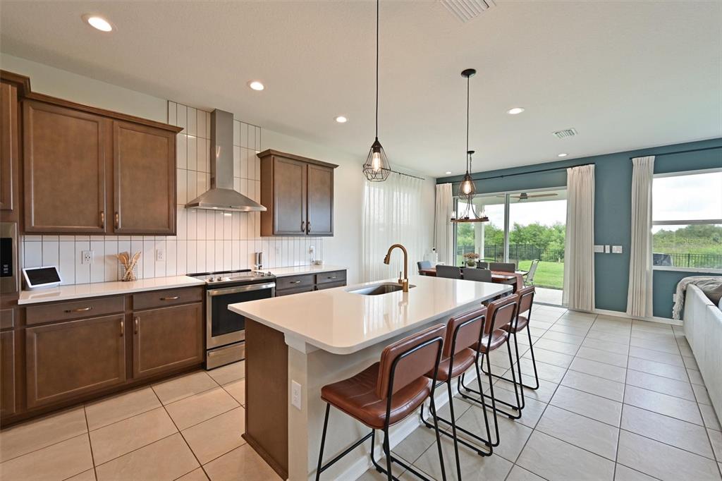 A kitchen with brown cabinets, white countertops, a center island, and a dining area — 11124 MOONSAIL DRIVE, PARRISH, FL