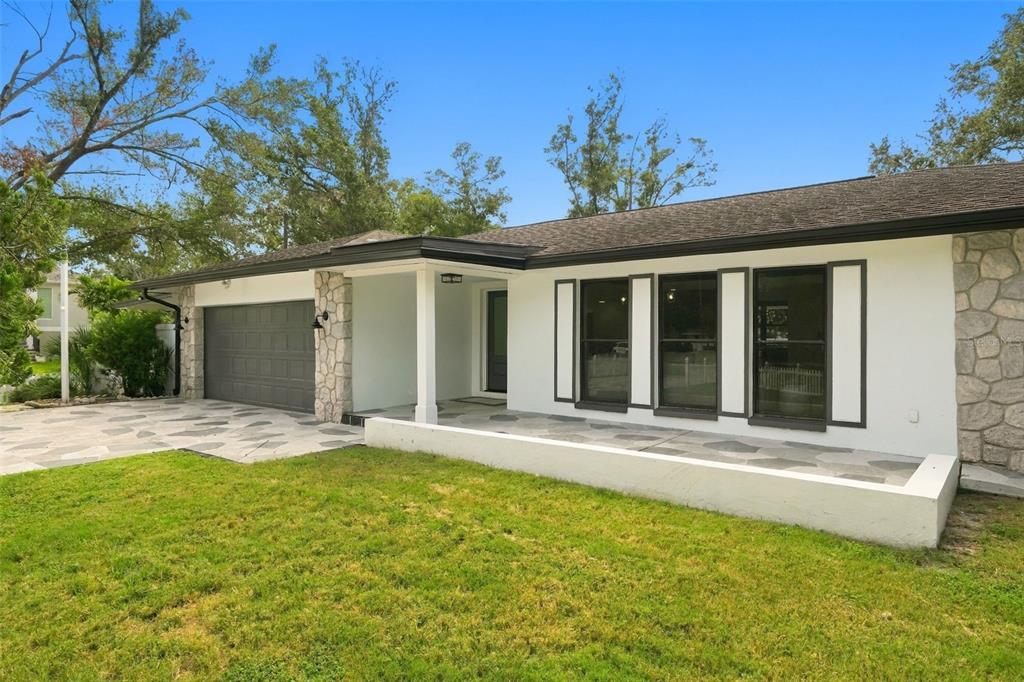 A single-story house with a white exterior, stone accents, a gray garage, and a front patio — 330 PATICA RD NE, ST PETERSBURG, FL