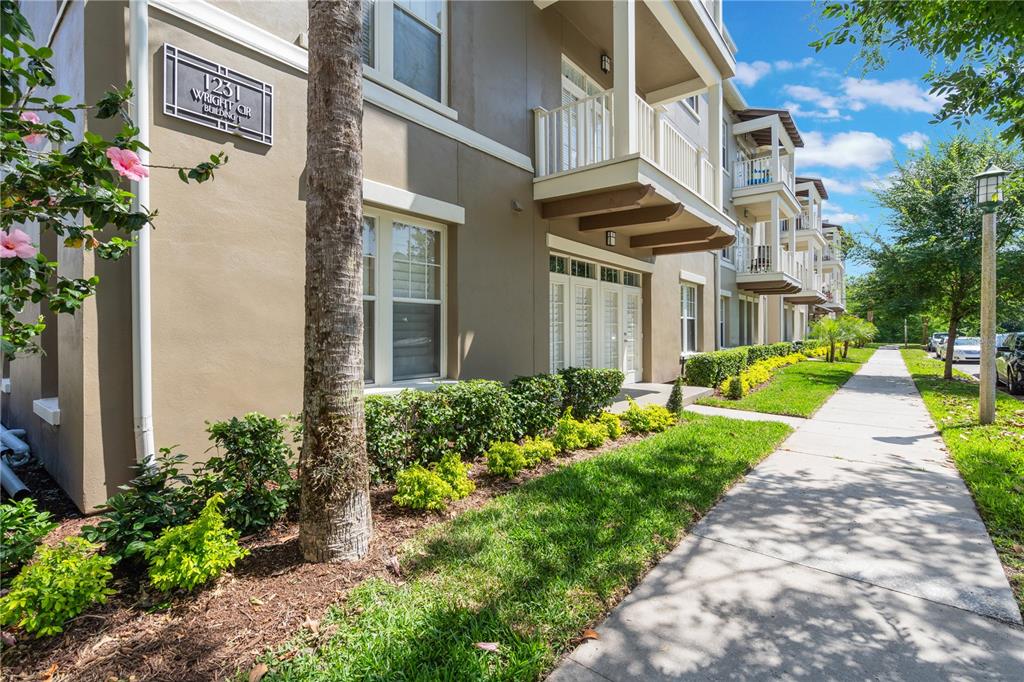 A multi-story apartment building exterior features tan stucco walls, balconies, and a sidewalk — 1231 WRIGHT CIRCLE UNIT 108, KISSIMMEE, FL