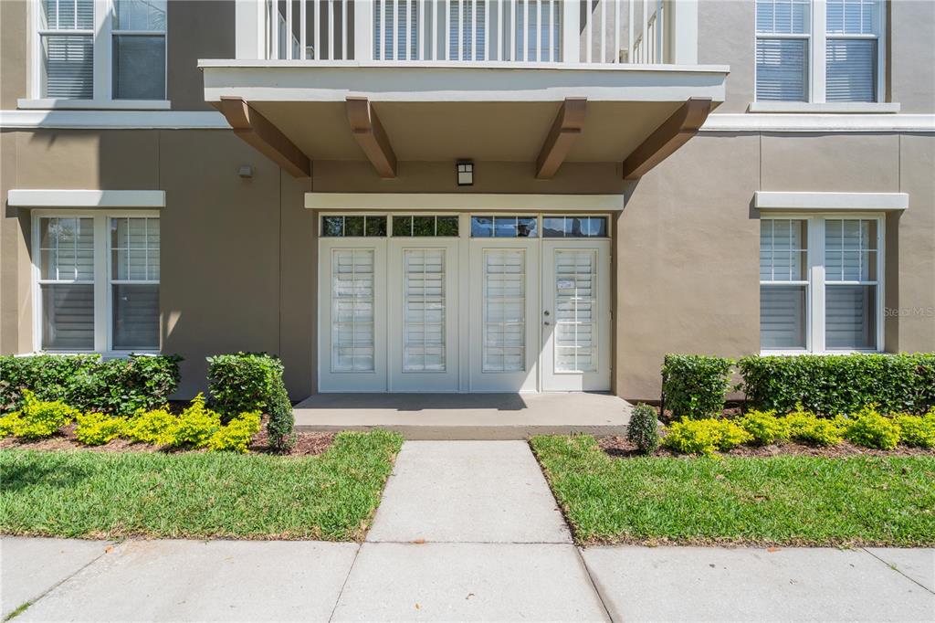 The exterior of a multi-story building features a ground-level entrance with glass-paned double doors — 1231 WRIGHT CIRCLE UNIT 108, KISSIMMEE, FL