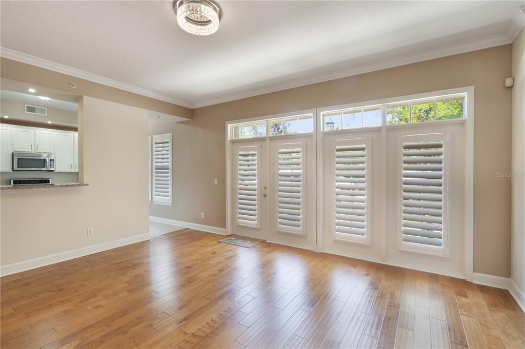 A living room with hardwood floors, a ceiling light fixture, and glass paneled doors — 1231 WRIGHT CIRCLE UNIT 108, KISSIMMEE, FL