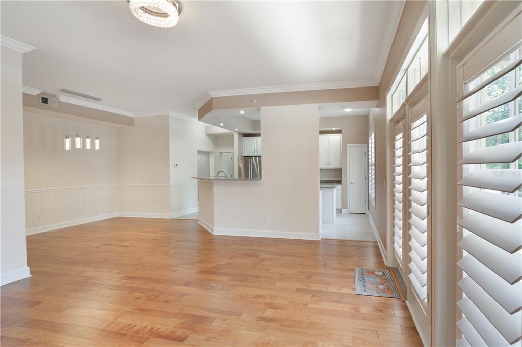 An open-concept living area with hardwood floors, a kitchen pass-through, and glass patio doors — 1231 WRIGHT CIRCLE UNIT 108, KISSIMMEE, FL