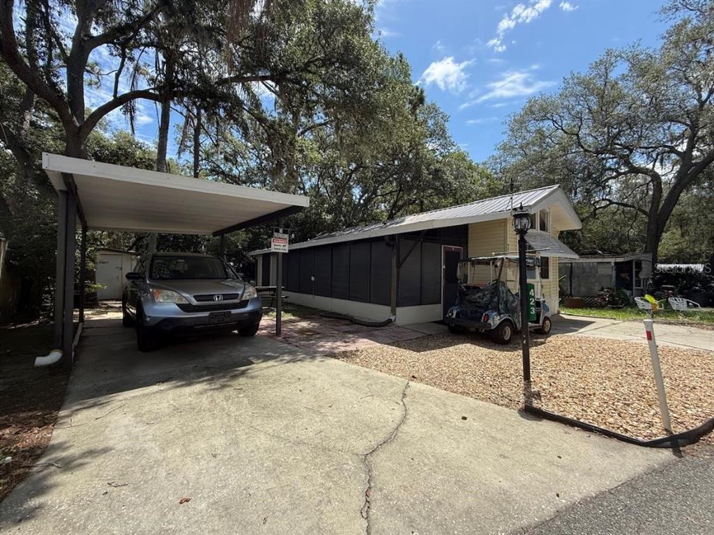 A single-story home with a metal roof, a carport, and a golf cart parked outside — 3000 CLARCONA ROAD UNIT 423, APOPKA, FL