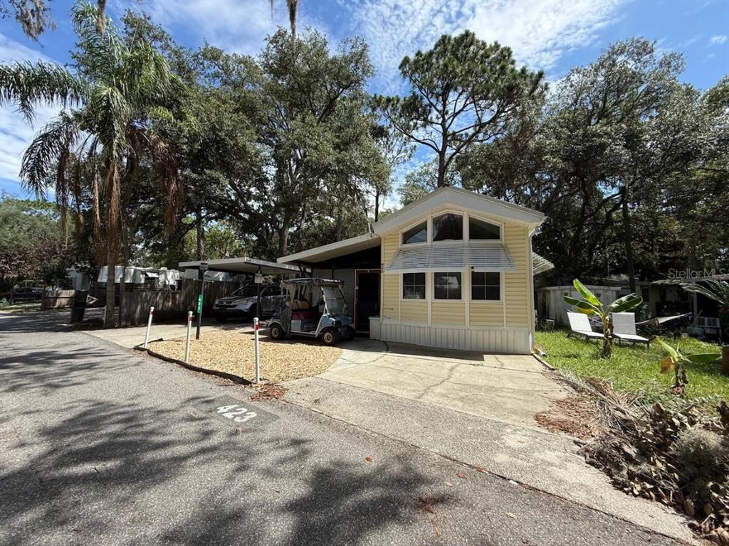 A yellow manufactured home with a carport, golf cart, and concrete driveway — 3000 CLARCONA ROAD UNIT 423, APOPKA, FL