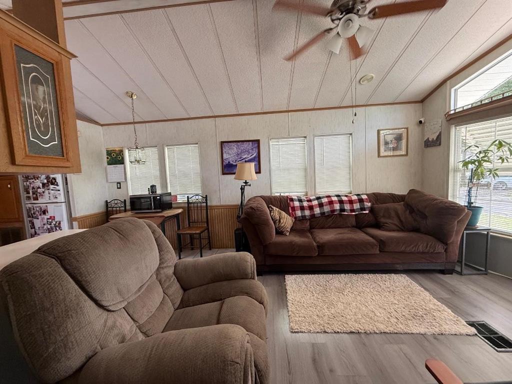 A living room features a brown sofa, a recliner, wood-look flooring, and a ceiling fan — 3000 CLARCONA ROAD UNIT 423, APOPKA, FL