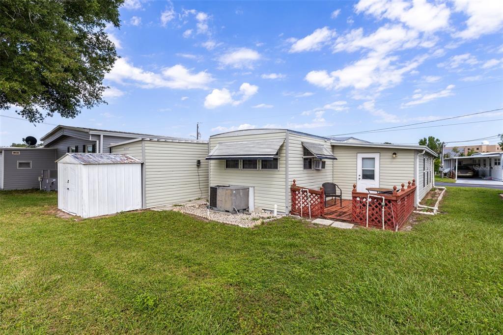 The exterior of a mobile home features a small wooden deck and a storage shed — 477 MARINA LANE, TAVARES, FL