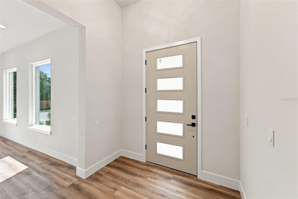 An entryway features a light-colored front door with five glass panels and wood-look flooring — 561 N THOMPSON ROAD, APOPKA, FL